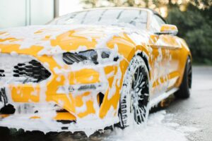 Cropped image of wheel of luxury yellow car in outdoors self-service car wash