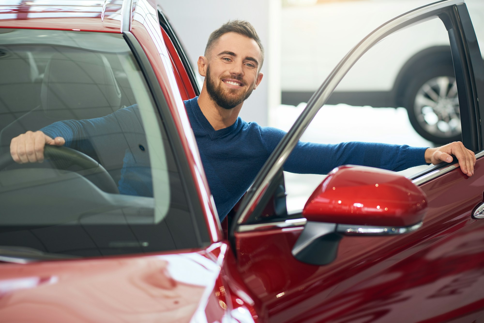 Happy man sitting in car in dealership